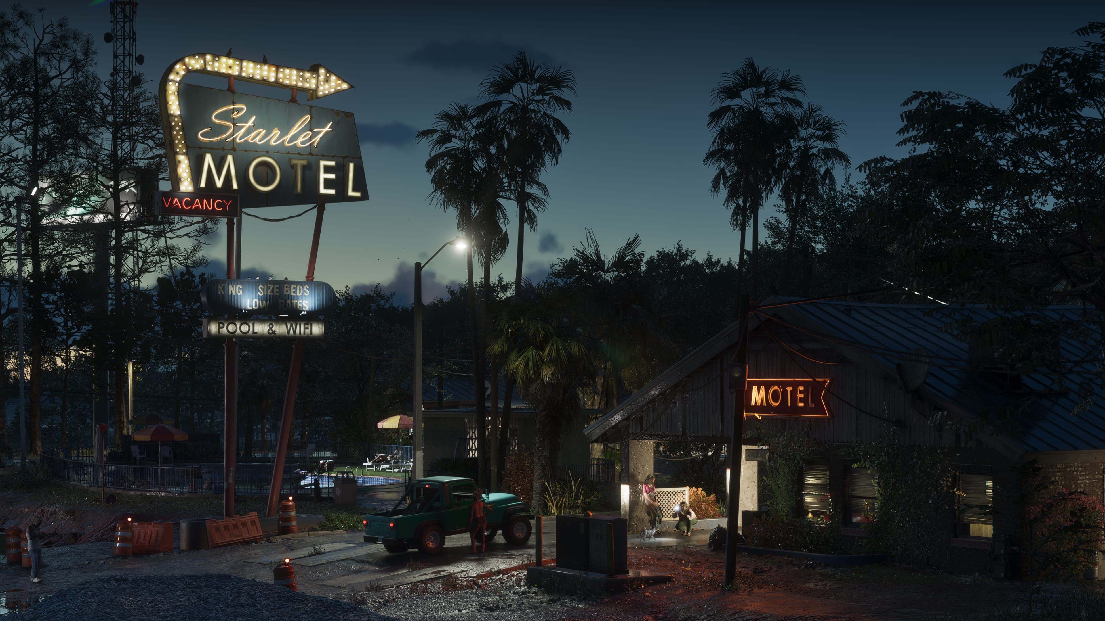 The Starlet Motel at night in Port Gellhorn, with palm trees, a pickup truck and illuminated vacancy signs.